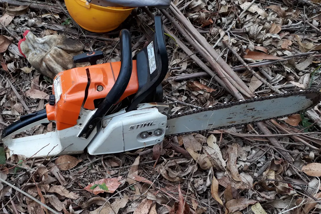 Motosserra apoiada no chão de uma área de corte florestal